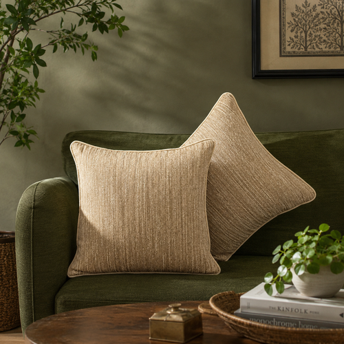 Champagne gold textured cushion cover styled on a dark olive green sofa in a modern luxury living room with natural light by Inara Home Decor.