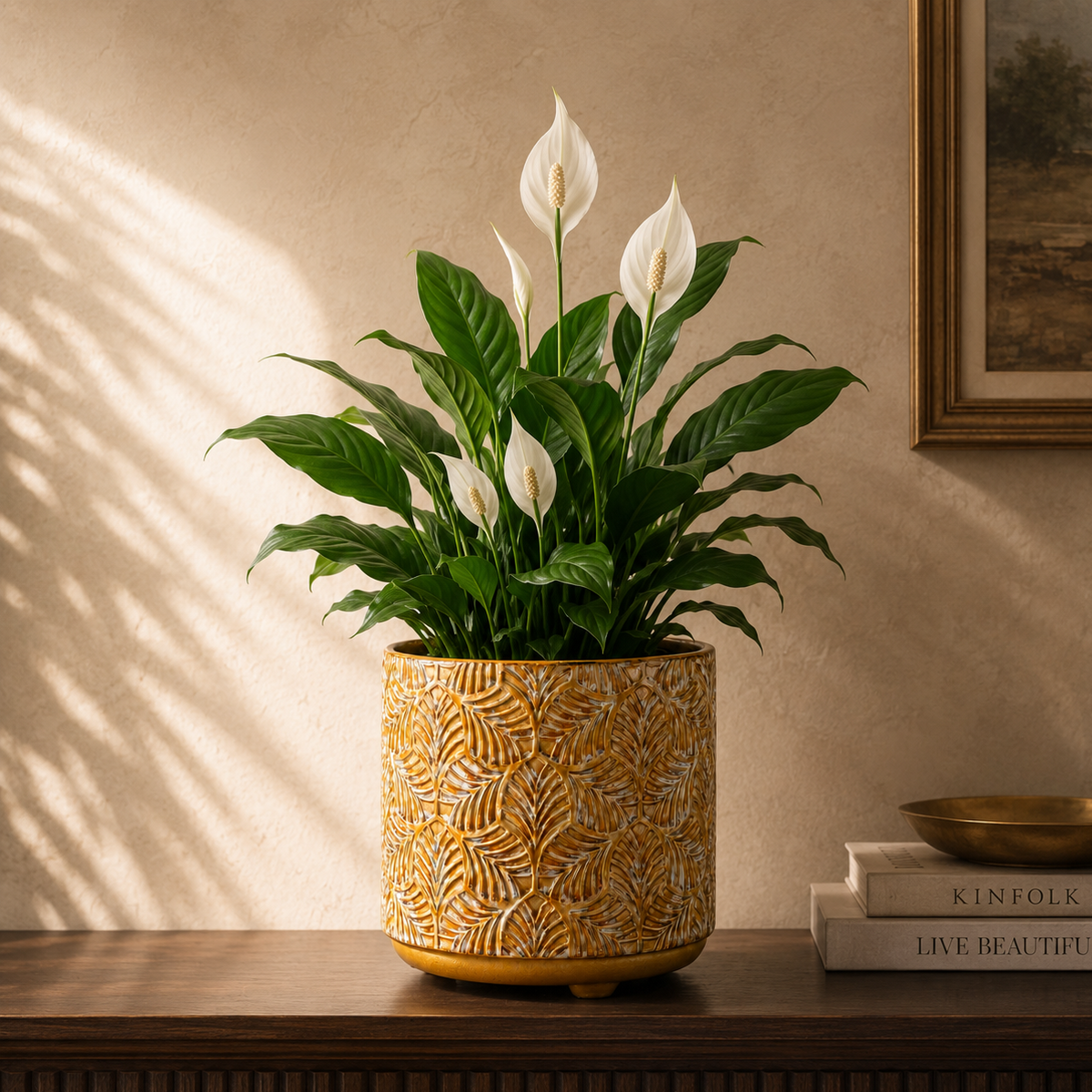 Mustard yellow embossed ceramic planter with leaf texture holding a Peace Lily, styled on a wooden console in a luxury living room.