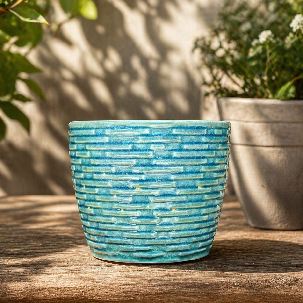 Turquoise textured ceramic planter displayed on a rustic wooden table in a sunlit garden setting with soft natural shadows.