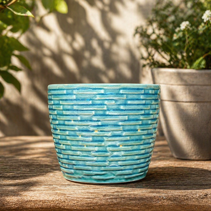 Turquoise textured ceramic planter displayed on a rustic wooden table in a sunlit garden setting with soft natural shadows.