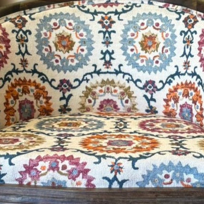 Close-up detail of multicolor floral patterned upholstery on a barrel accent chair featuring intricate medallion motifs in blue, rust, and beige tones.