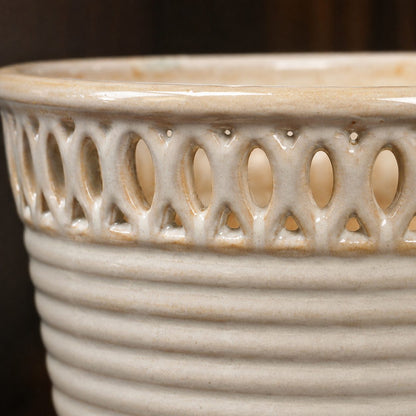 Close-up of the decorative cutwork rim and ribbed texture on a cream glazed ceramic planter.