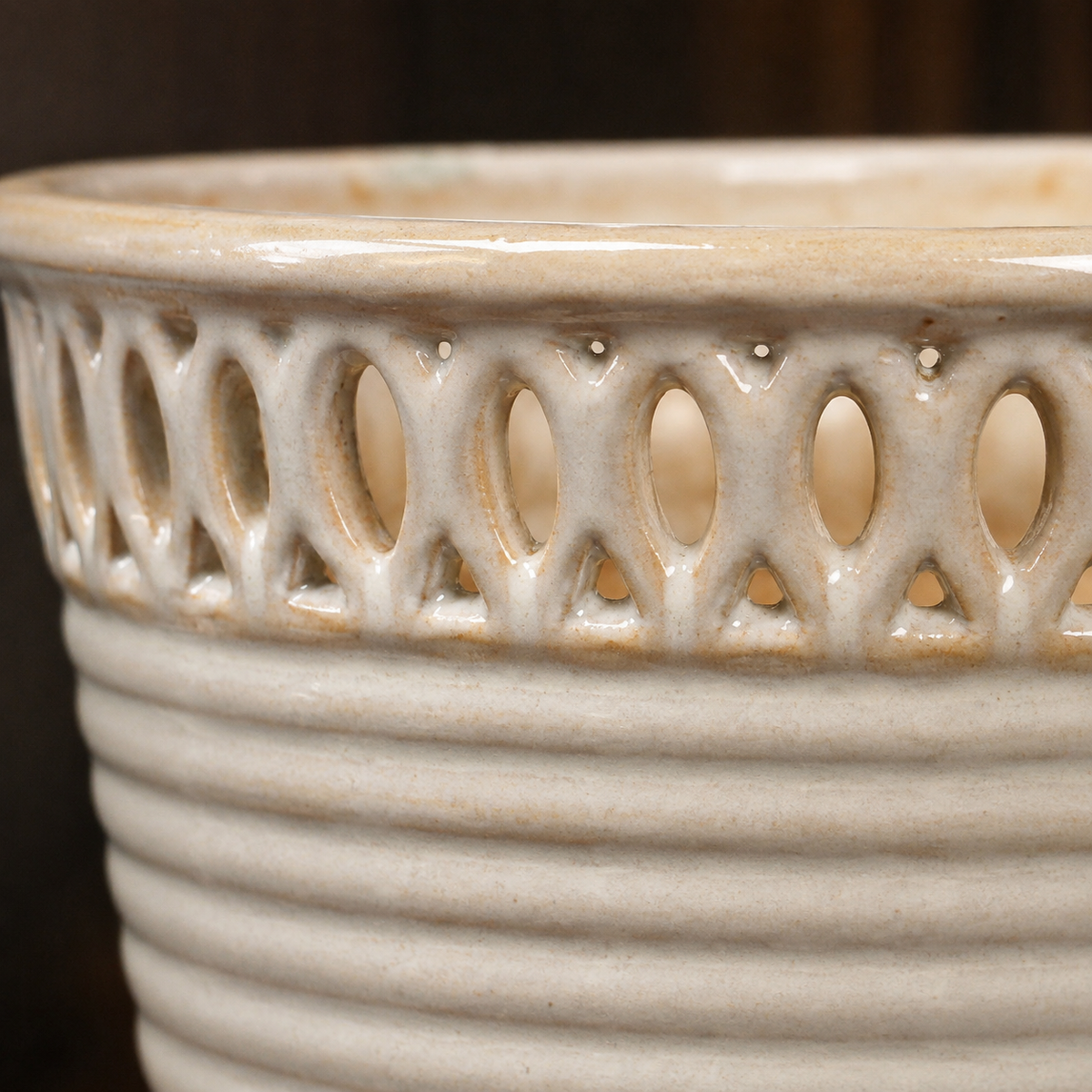 Close-up of the decorative cutwork rim and ribbed texture on a cream glazed ceramic planter.
