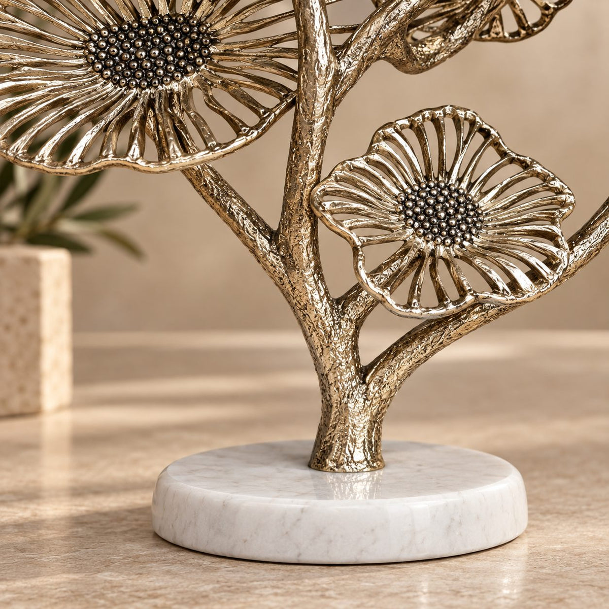 Close-up of natural white marble base and textured gold metal stem of a luxury decorative floral sculpture.