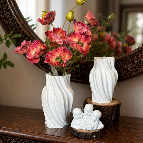 White spiral ribbed ceramic vases with pink floral arrangement styled on a carved wooden console table with an ornate round mirror in warm natural light.