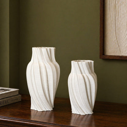 Set of white spiral ribbed ceramic vases styled on a dark polished wood console against an olive green wall in a modern minimalist interior.