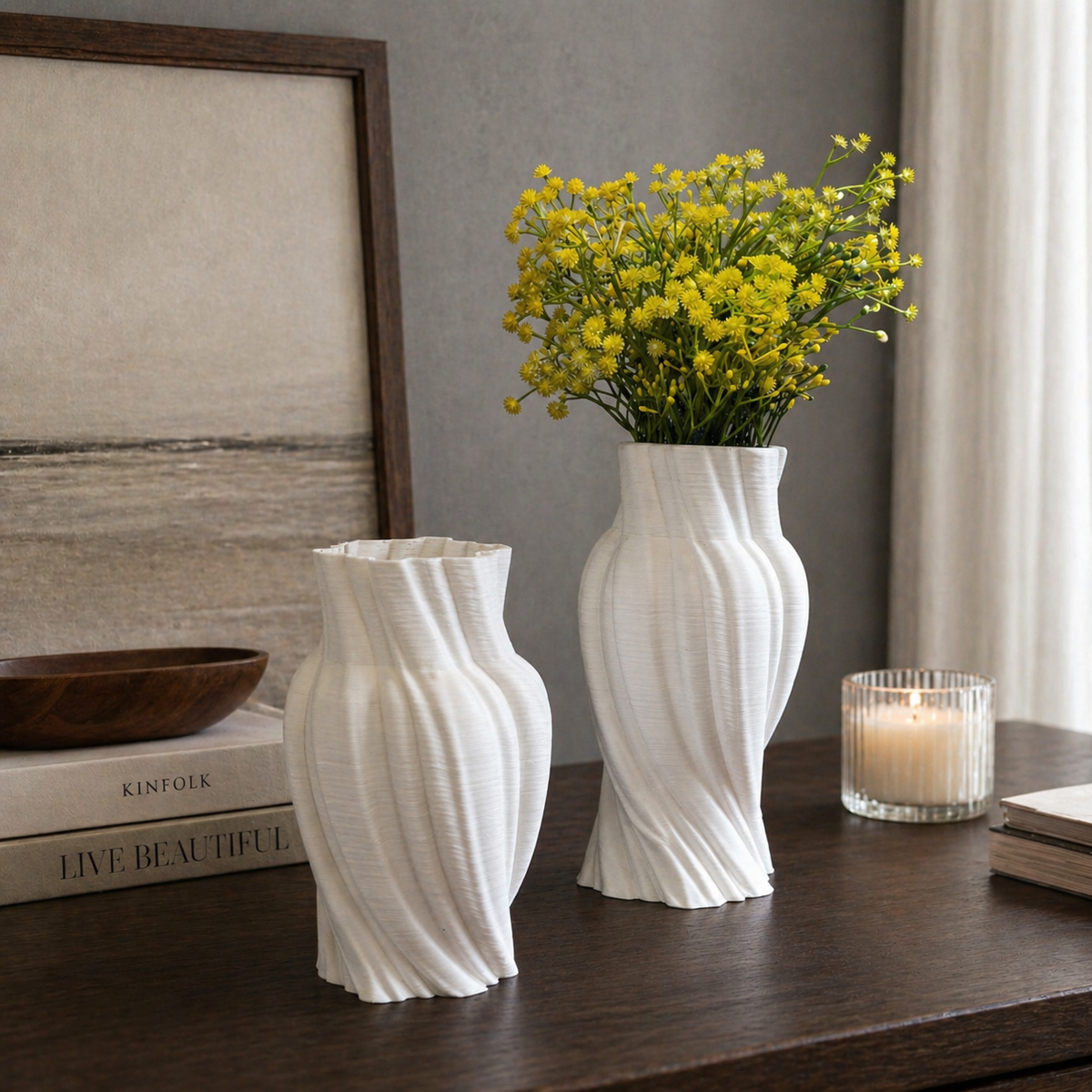 Set of white spiral ribbed ceramic vases styled on a dark wood tabletop with yellow flowers, grey textured wall, and modern minimalist décor.