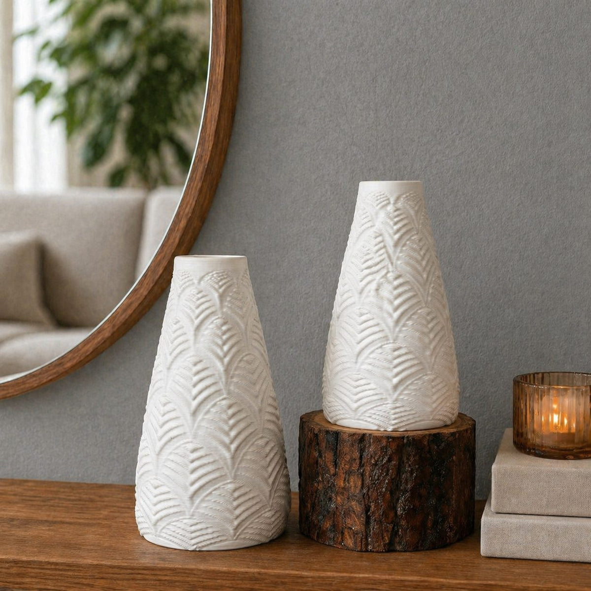 Set of white textured ceramic vases styled on a wooden console with a rustic wood pedestal, grey wall backdrop, round mirror, and warm candle décor in a modern minimalist interior.