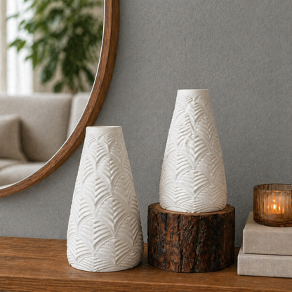 Set of white textured ceramic vases styled on a wooden console with a rustic wood pedestal, grey wall backdrop, round mirror, and warm candle décor in a modern minimalist interior.