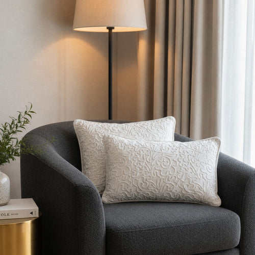 Ivory embroidered velvet cushion covers styled on a charcoal accent chair in a modern luxury living room with soft neutral décor and elegant textured detailing.