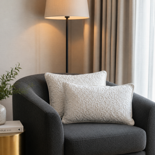 Ivory embroidered velvet cushion covers styled on a charcoal accent chair in a modern luxury living room with soft neutral décor and elegant textured detailing.