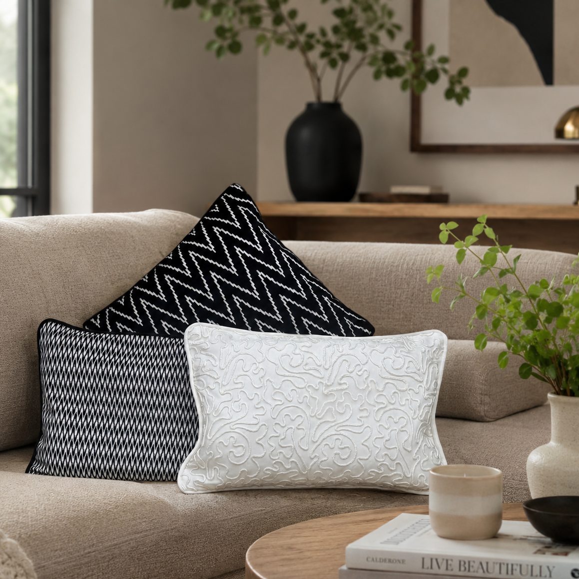 Black and white designer cushion covers styled on a beige sofa in a modern luxury living room, featuring textured patterns and elegant contemporary home décor.