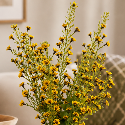 Close-up of delicate yellow wildflower artificial stems arranged indoors with soft neutral home decor background.