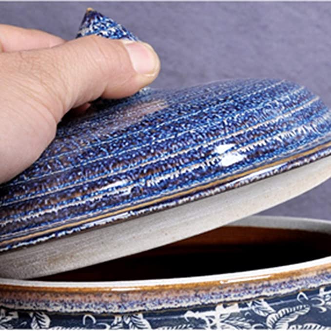 Close-up of a hand lifting the lid of a blue textured ceramic jar, showcasing the intricate ridged pattern and speckled glaze.